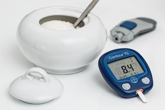 A small open dish with sugar and blood glucose meter