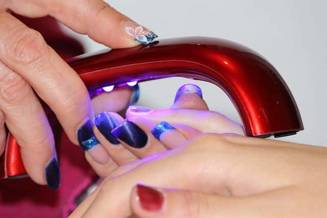 A woman curing gel nail polish with UV nail polish dryer 